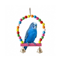 A blue budgerigar perched on a pink wooden toy bar with two small gold bells and a colorful circular hoop of painted beads above it, isolated on a white background.